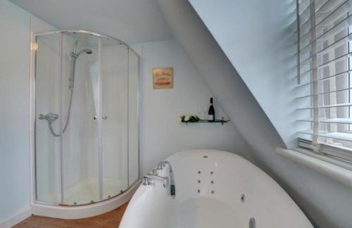 ein weißes Bad mit einer Dusche und einer Badewanne in der Unterkunft Northfield Cottage in Ilfracombe