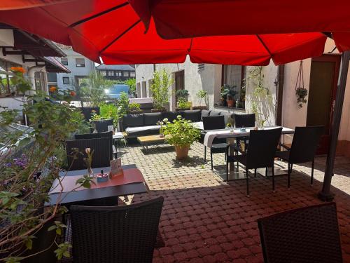 a patio with tables and chairs and a red umbrella at Hotel Zum Löwen in Mörfelden-Walldorf