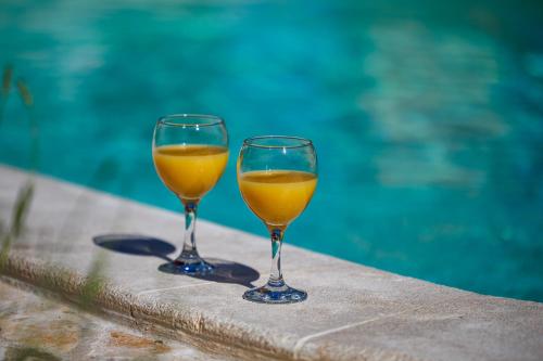 two glasses of orange wine sitting next to a swimming pool at Villa Ivona with pool in Poljica