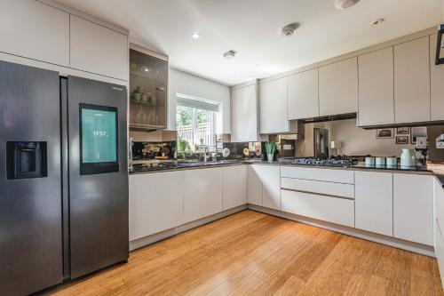 a kitchen with white cabinets and a stainless steel refrigerator at Royal Windsor Manor House in Windsor