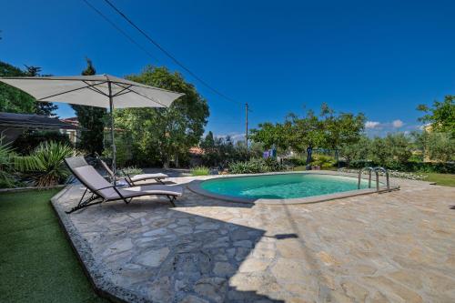a chair and an umbrella next to a swimming pool at Villa Ivona with pool in Poljica