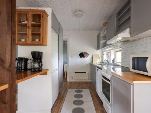 a kitchen with white appliances and wooden cabinets at Chalet Harge Sörgård by Interhome in Hammar