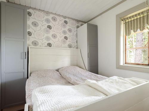 a white bedroom with a bed and a window at Chalet Harge Sörgård by Interhome in Hammar