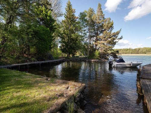 a boat is docked at a dock on a river at Chalet Harge Sörgård by Interhome in Hammar