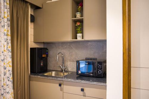 a kitchen counter with a microwave and a sink at Serene 2BHK with Garden and Hilltop Jacuzzi in Palāhu