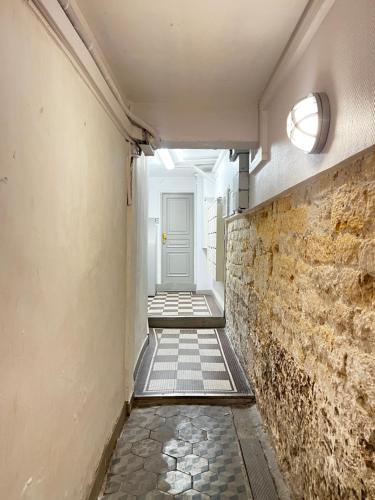 un couloir avec un mur en briques et une porte blanche dans l'établissement Studio Exceptionnel au Marais, à Paris