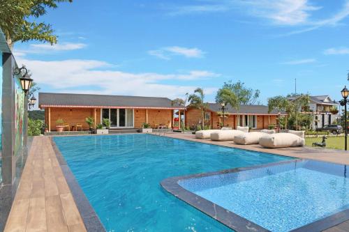 a swimming pool with blue water in front of a house at Serene 2BHK with Garden and Hilltop Jacuzzi in Palāhu