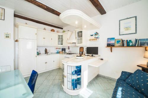 a kitchen with white cabinets and a blue couch at Perfume House in Marciana