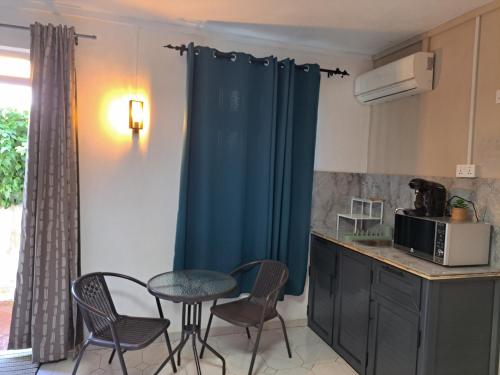 a kitchen with a table and chairs and a blue curtain at R Garden Studio 1 - Ensuite avec accès privé et indépendant in Baie du Tombeau