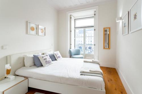 a white bedroom with a large bed and a chair at Restauradores Prime Loft in Lisbon