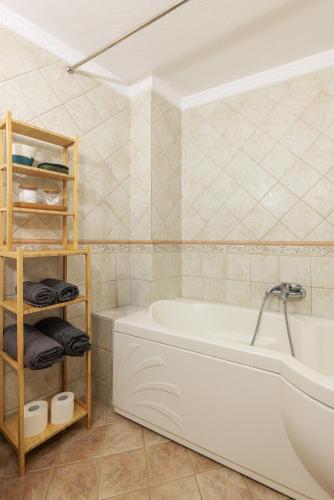 a bathroom with a white tub and a tiled wall at Centaurus Apartment in Old Town with a big Terrace and view to Olympus Mountain ! in Thessaloniki