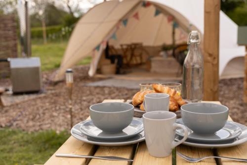 a table with cups and plates of food on it at Broadleaves Luxury Glamping in Ticknall