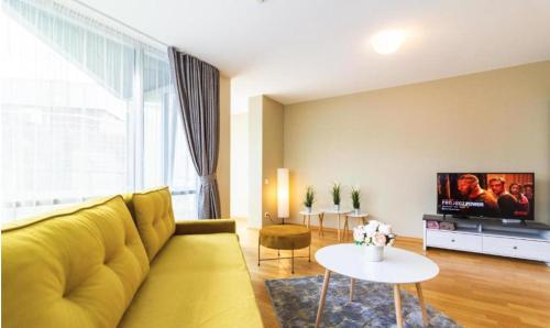 a living room with a yellow couch and a table at Elija Swan-Toy Apartments in Šventoji
