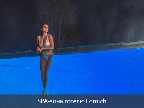 a woman in a bikini standing on a swimming pool at Black & White Villas by Fomich Hotels Group in Bukovel