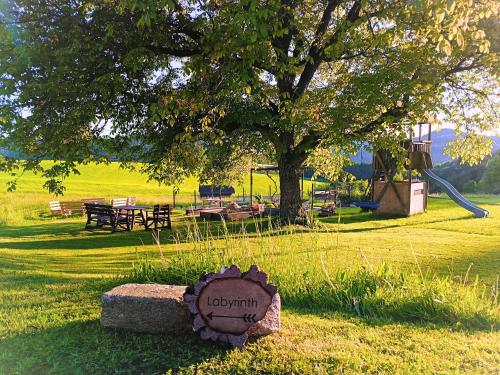 a park with a tree and a bench in the grass at Natur Erlebnishof Aumayr in Gutau