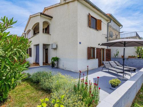 a house with an umbrella and a patio at Holiday Home Lorena by Interhome in Raša