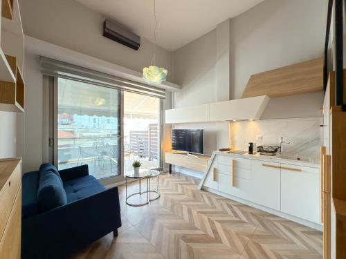 a living room with a blue couch and a kitchen at Luxury Downtown Apartment With Seaview E2 in Thessaloniki
