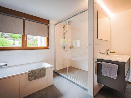 a bathroom with a tub and a sink and a shower at Chalet Le Souvenir by Interhome in Ovronnaz
