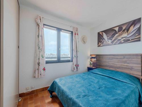 une chambre avec un lit bleu et une fenêtre dans l'établissement Apartment Coudalère-Les Hébrides-4 by Interhome, au Barcarès