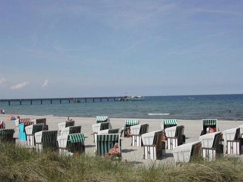 a group of lawn chairs on a beach with a pier at Kirchblick an der Ostsee - ABC277 - nur Feriengäste! in Hohenkirchen