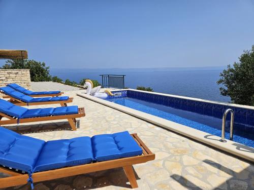 a swimming pool with blue lounge chairs and the ocean at Holiday Home Brankovi Dvori by Interhome in Prigradica