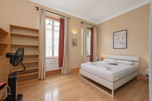 une chambre avec un lit blanc et une grande fenêtre dans l'établissement Grand appartement dans la vieille ville, à Menton
