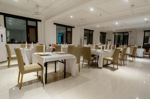 a large dining room with white tables and chairs at Hunters Royal Hotel in Trofwi
