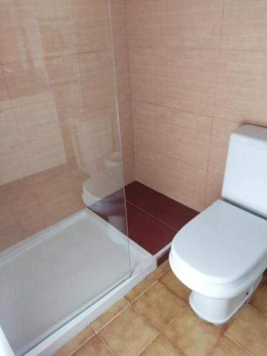 a bathroom with a toilet and a glass shower at Chalet calan Bosch Menorca in Cala'n Bosch