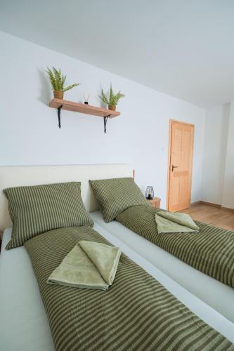two beds with green pillows in a bedroom at Harmónia Ház in Orfű