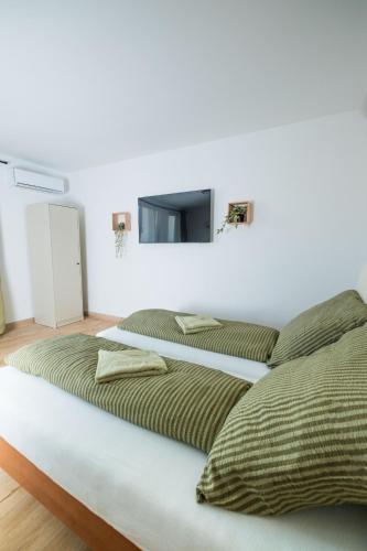 a bedroom with two beds and a tv on the wall at Harmónia Ház in Orfű