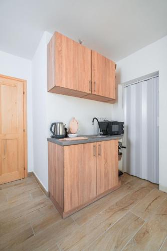a kitchen with wooden cabinets in a room at Harmónia Ház in Orfű