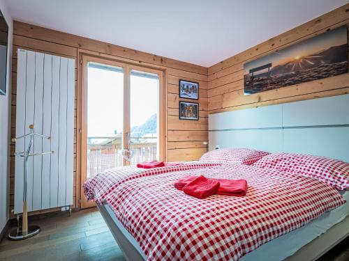 a bedroom with a bed with a red and white checkered blanket at Chalet L'Eden by Interhome in Ovronnaz