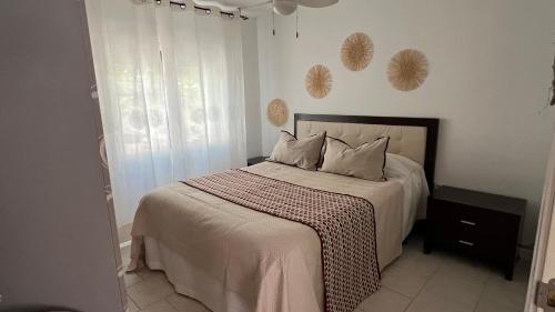 ein Schlafzimmer mit einem Bett mit weißen Laken und einem Fenster in der Unterkunft La Casita de Noe con vista al Pantano de San Juan in San Martín de Valdeiglesias