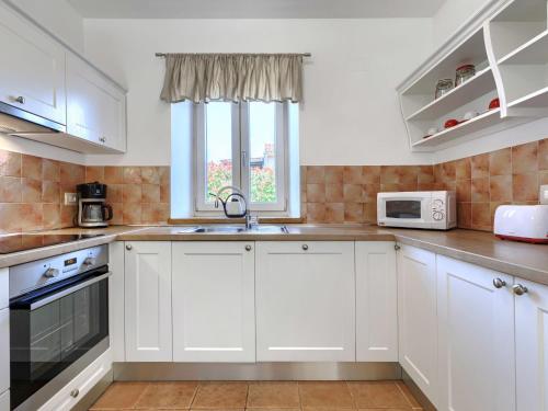 a kitchen with white cabinets and a sink and a window at Holiday Home Villa Samanta by Interhome in Momjan