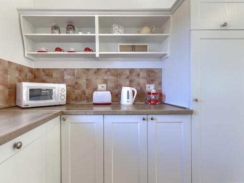 a kitchen with white cabinets and a microwave at Holiday Home Villa Samanta by Interhome in Momjan