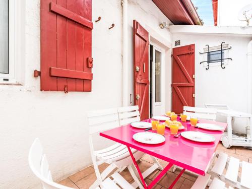 une table rouge avec des chaises blanches et une porte rouge dans l'établissement Apartment Goyenetche by Interhome, à Saint-Jean-de-Luz
