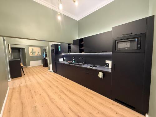 una grande cucina con armadi neri e pavimento in legno di HOME1 - District Twelve Boutique Hostel a Vienna