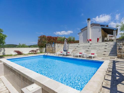 a swimming pool with chairs and a house at Holiday Home Villa Samanta by Interhome in Momjan