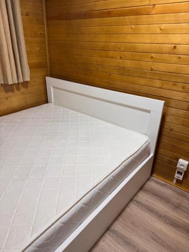 a bed in a room with a wooden wall at А фреймы на Иссыкуле in Chon-Sary-Oy