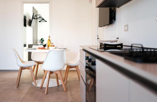 a kitchen with a table and white chairs in it at Eleia Mirea in Monopoli