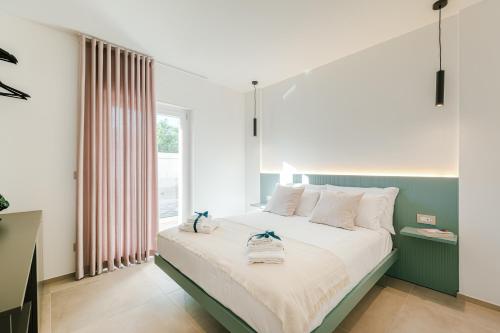 a bedroom with a bed with white sheets and a window at Eleia Mirea in Monopoli