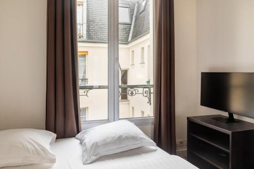 - une chambre avec une fenêtre, un lit et une télévision dans l'établissement Pied-a-terre near Bastille & Voltaire Paris 11th, à Paris