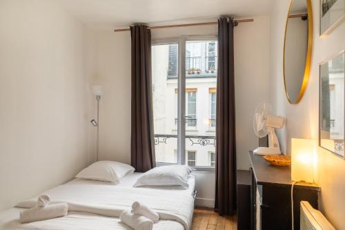 deux lits dans une chambre avec une fenêtre dans l'établissement Pied-a-terre near Bastille & Voltaire Paris 11th, à Paris