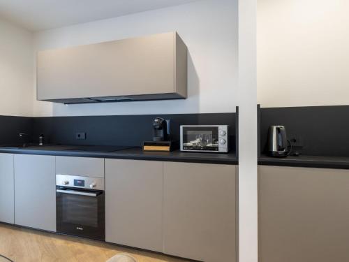 a kitchen with white and black cabinets and a microwave at Apartment Marconi by Interhome in Chiavenna