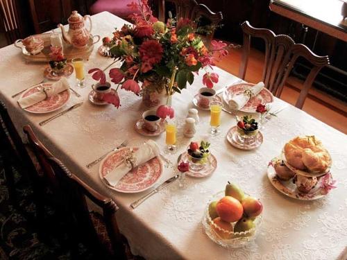 a table with plates of food and flowers on it at Fisher House Victoria Bed and Breakfast in Victoria