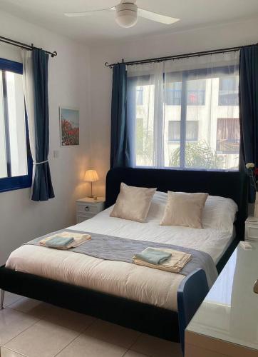a bedroom with a large bed with blue curtains at paphos pool view gem - cozy 1 bed Apartment in Paphos