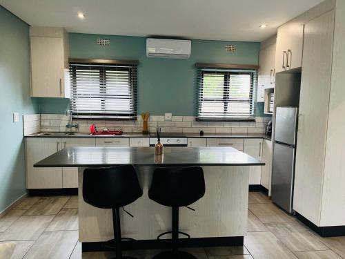 una cocina con una isla grande con 2 taburetes en Heavenly Towers, en Mbazwana