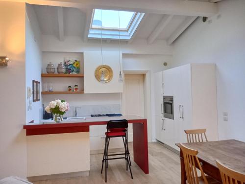 a kitchen with a red and white counter and a table at Mansarda in Piazzetta Centro Storico in Manerba del Garda