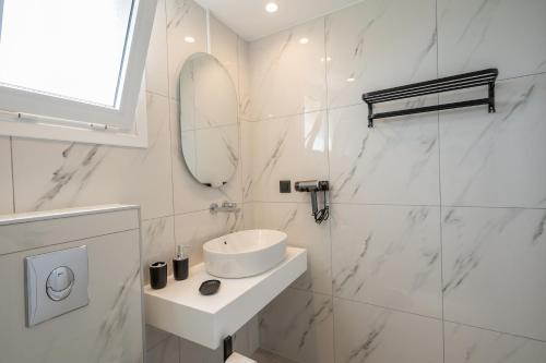a white bathroom with a sink and a mirror at Stone and Sea Kos Oasis in Kos Town