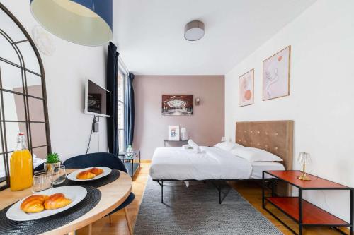- une chambre avec un lit et une table avec du pain dans l'établissement 205 - studio cosy vue sur le musee - Paris 5 - FLAT-GUEST, à Paris